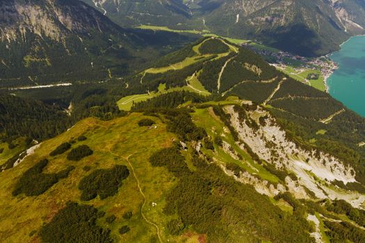 Stunning aerial view of the lush Tyrolean mountains and turquoise lake in Jenbach, Austria.