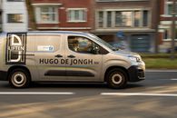 Dynamic shot of a branded minivan captured in motion on a city street during daylight.
