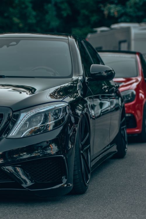 Free Close-up of a sleek black luxury car parked on a city street. Stock Photo