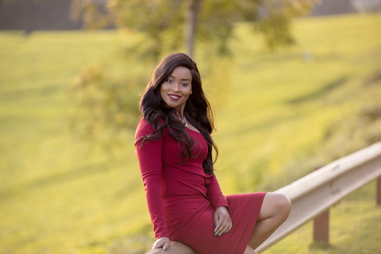 Woman In Red Dress Sitting On Road Barrier 