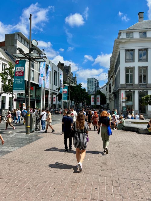Free Bustling city street scene with people walking among modern buildings under a clear blue sky. Stock Photo