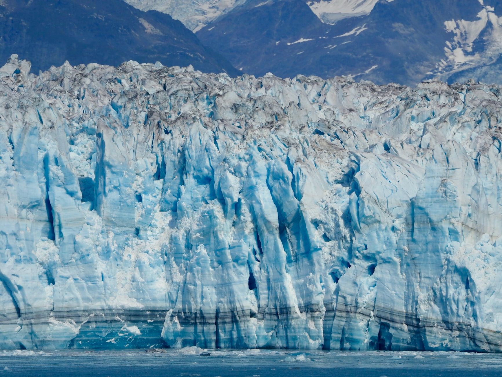 Stunning view of an Alaskan glacier with rugged mountains in the background, illustrating nature's beauty.