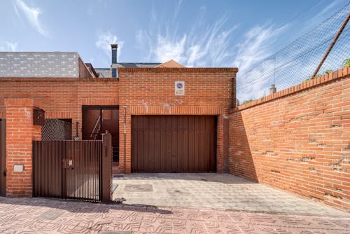 Brown Brick House and Concrete Driveway Under Blue Sky