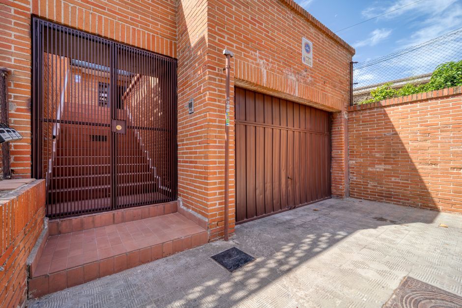 Fotomural Fachada de ladrillo moderno con puerta de metal y escalera, fotografiada durante el día para diseño arquitectónico urbano.