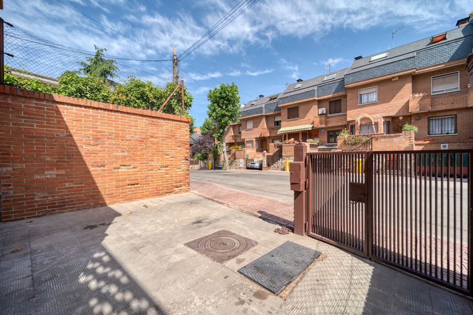Fotomural Vecindario residencial soleado con casas de ladrillo y árboles verdes en un día despejado.