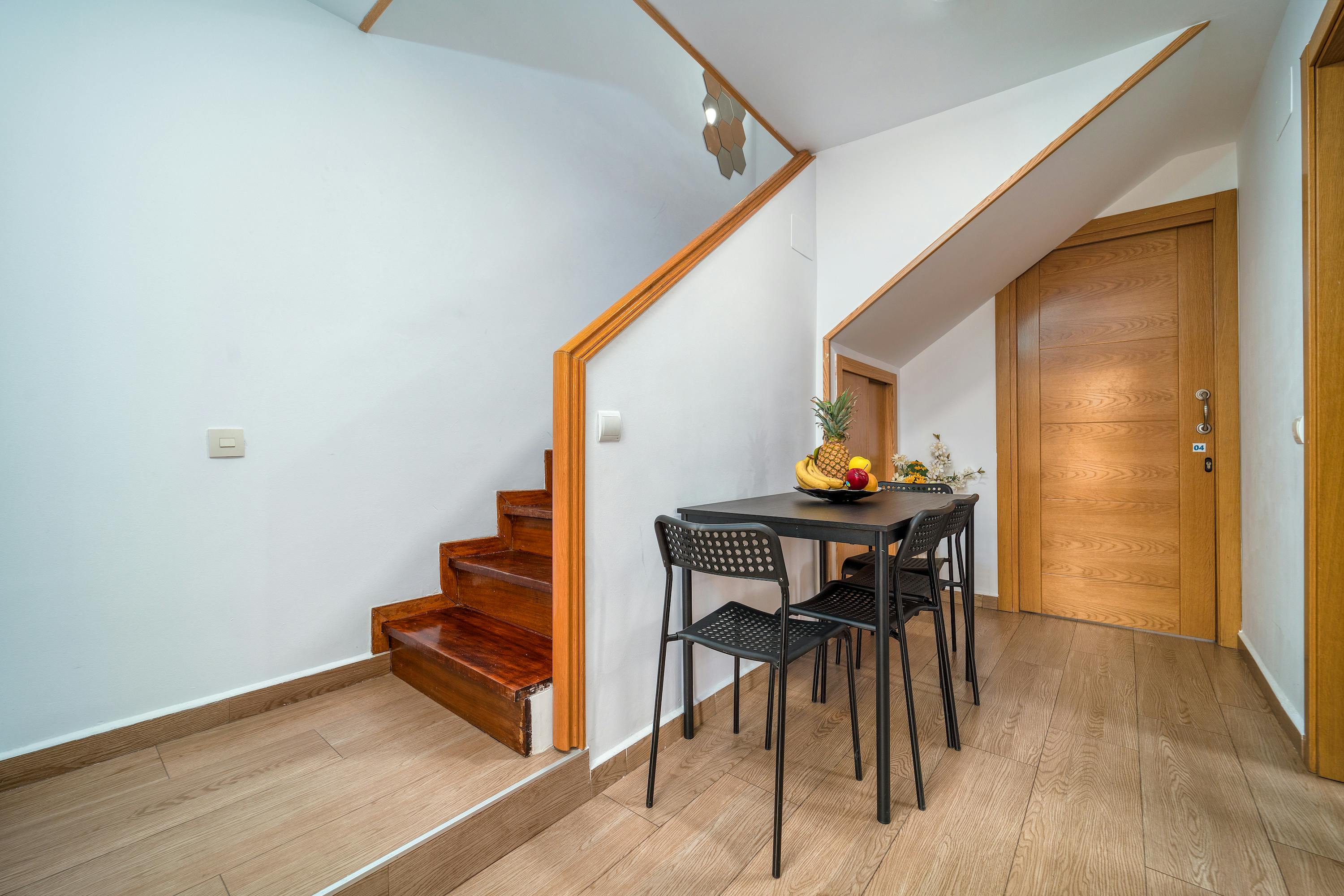 Free Clean and minimalist interior with wooden accents, featuring a small dining area under the stairs. Stock Photo