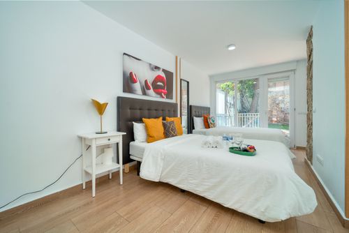 Free Contemporary minimalist bedroom with twin beds, art decor, and natural lighting from glass doors. Stock Photo