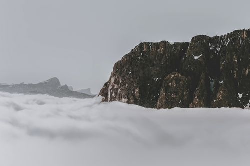 Free Majestic Dolomites mountain peak rising through a sea of clouds, creating a serene and dramatic winter scene. Stock Photo
