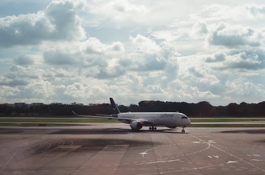 A Lufthansa aircraft on the airport tarmac, with clouds in the background.