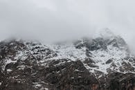 薄雾和云层笼罩着白雪皑皑的山脉，营造出雄伟的自然景观
