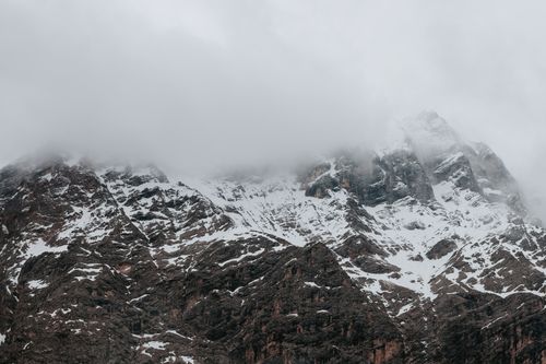 Free Snow-covered mountains shrouded in mist and clouds create a majestic natural scene. Stock Photo