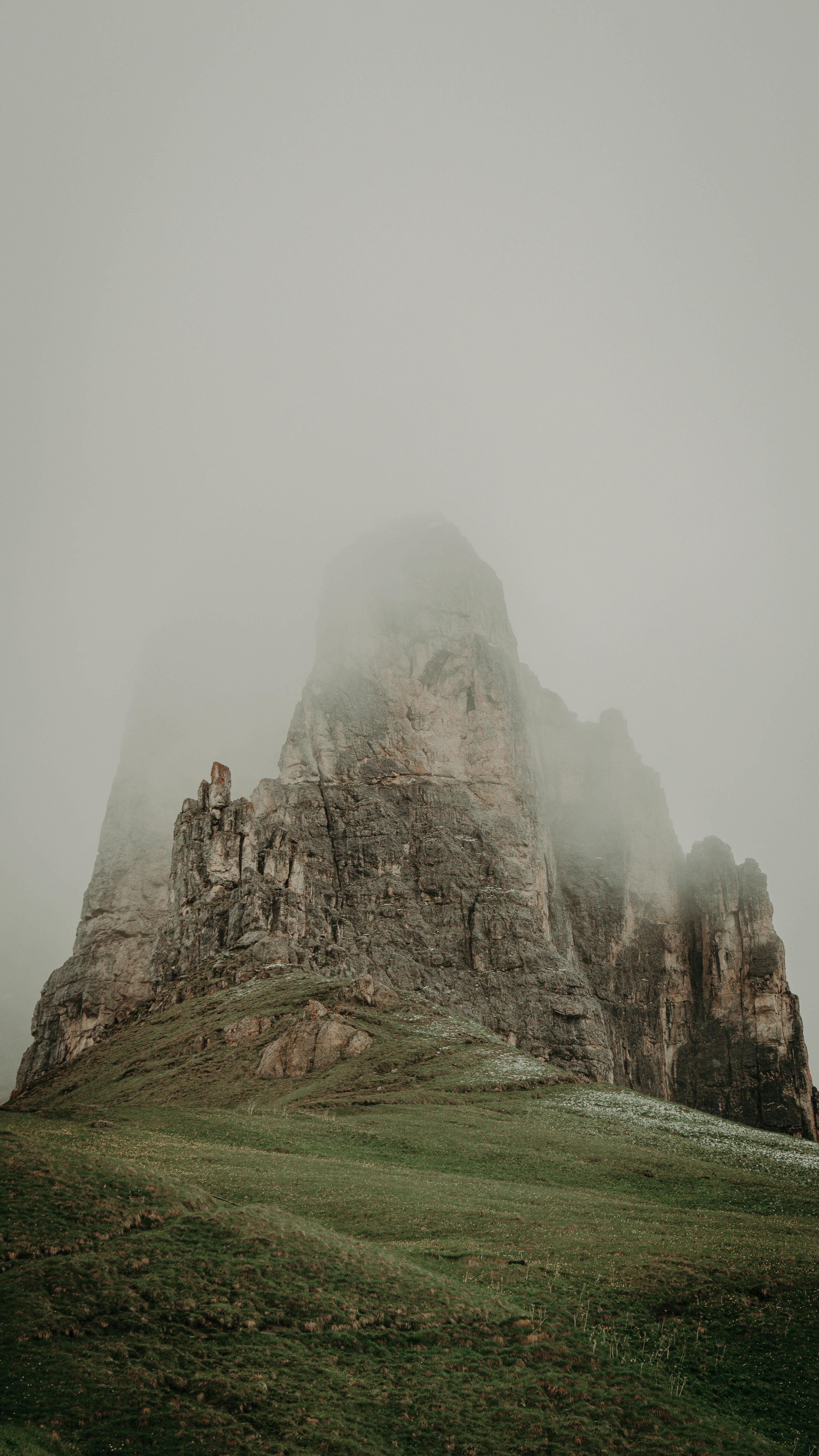 Foggy mountain landscape featuring rugged cliffs and lush greenery, capturing nature's ethereal beauty.