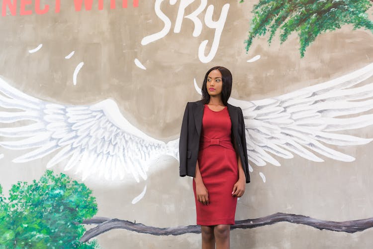 Woman In Red Dress With Black Blazer Standing On Mural Wall 