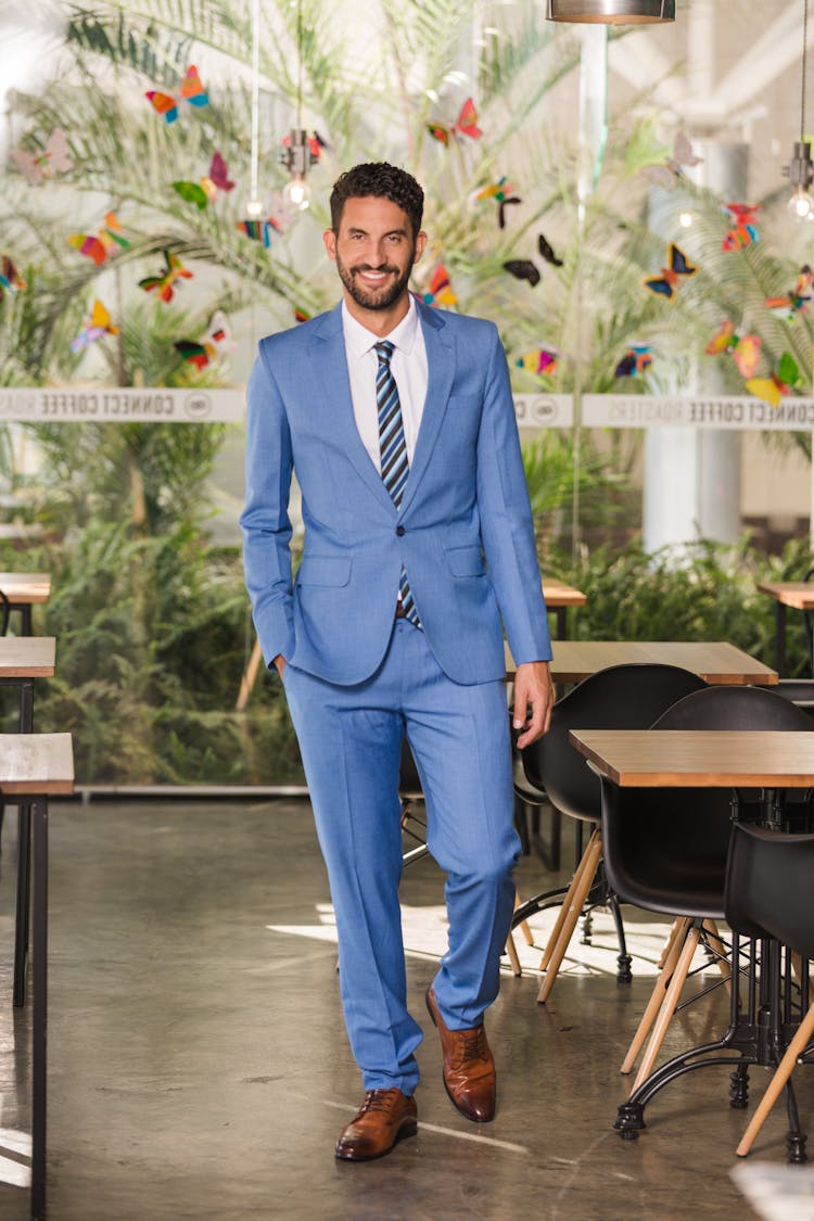 Man In Blue Suit Walking Near Table And Chairs