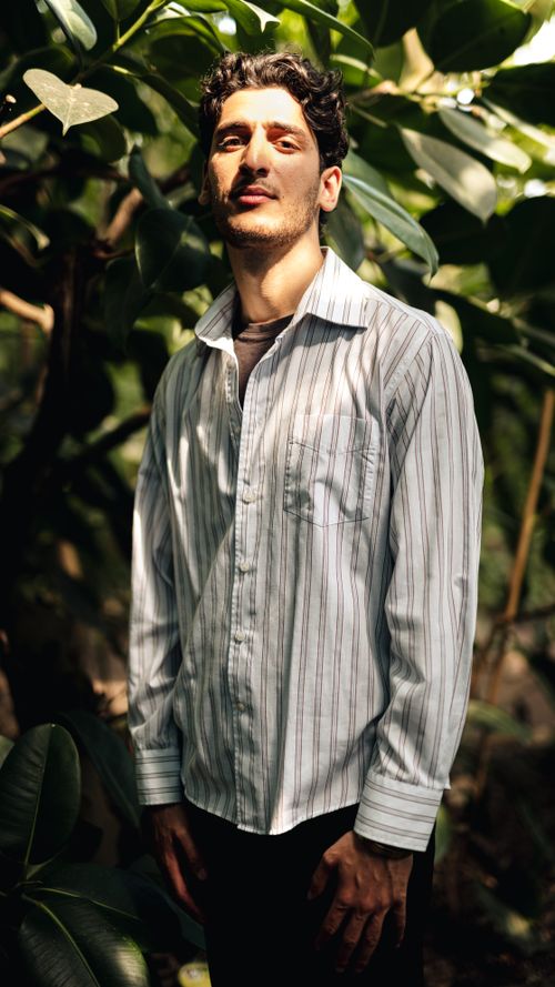 Free A portrait of a man wearing a striped shirt, illuminated by natural sunlight in an outdoor setting. Stock Photo