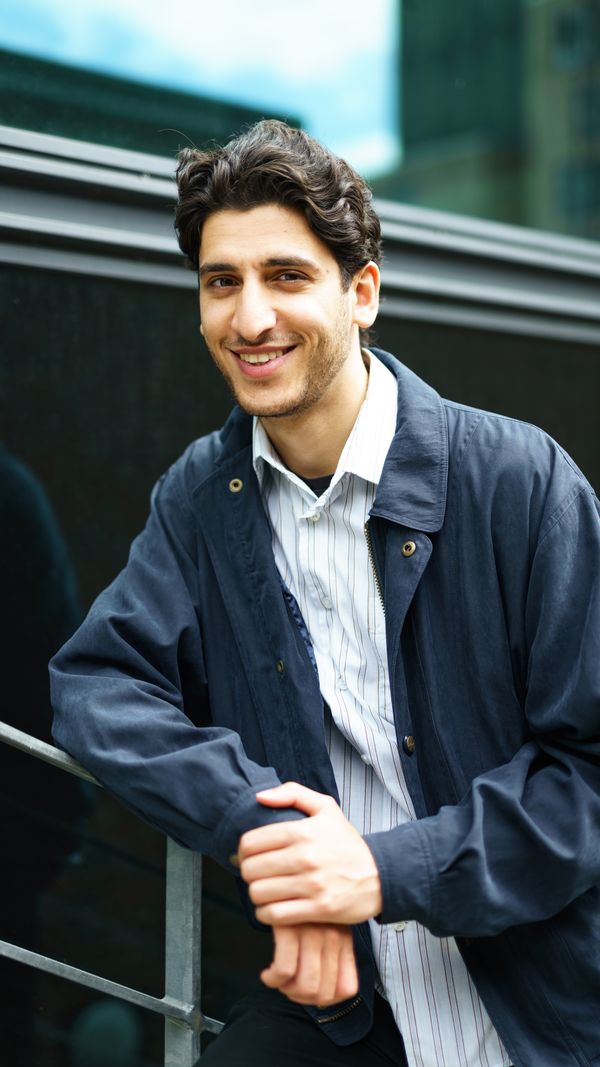 A colleague leaning on a rail outside the office, photo by Skildring by Andreas Ellegaard on Pexels