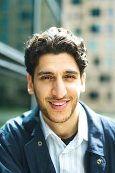 Portrait of a smiling man outdoors in an urban setting with natural daylight.