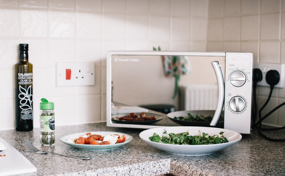 Two White Ceramic Plates Near Microwave On Counter Top