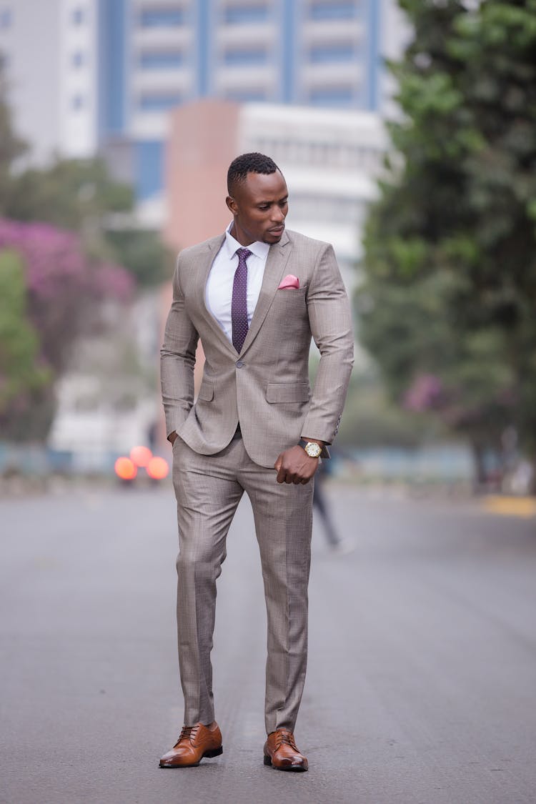 A Man Wearing Light Gray Suit Standing In The Middle Of Road