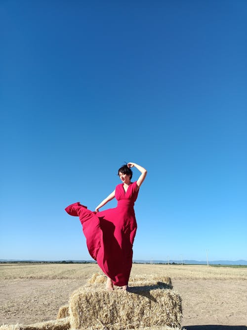 A Woman Standing on Haystack while Posing