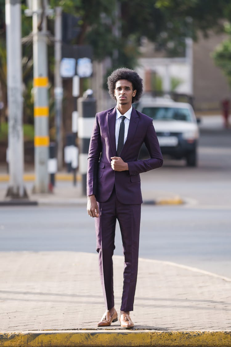 A Man In Purple Suit And Purple Pants Standing On The Street