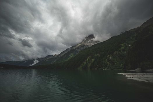 Capture of a moody mountain landscape with dense clouds and serene lake waters.