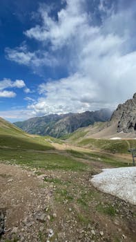 Breathtaking mountain valley under blue sky with lush greenery and rocky peaks.