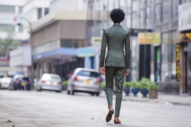 Back View Of A Man In A Suit Walking On A Road