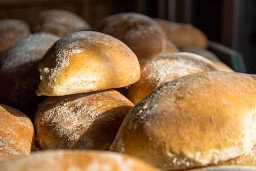 Free Close-up of freshly baked bread rolls in warm sunlight, highlighting the golden crusts and inviting texture. Stock Photo