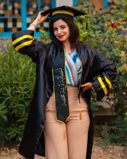 Free Young woman in graduation attire smiles confidently outdoors, showcasing achievement and joy. Stock Photo