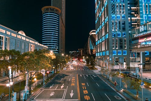 A Road Between City Buildings at Night