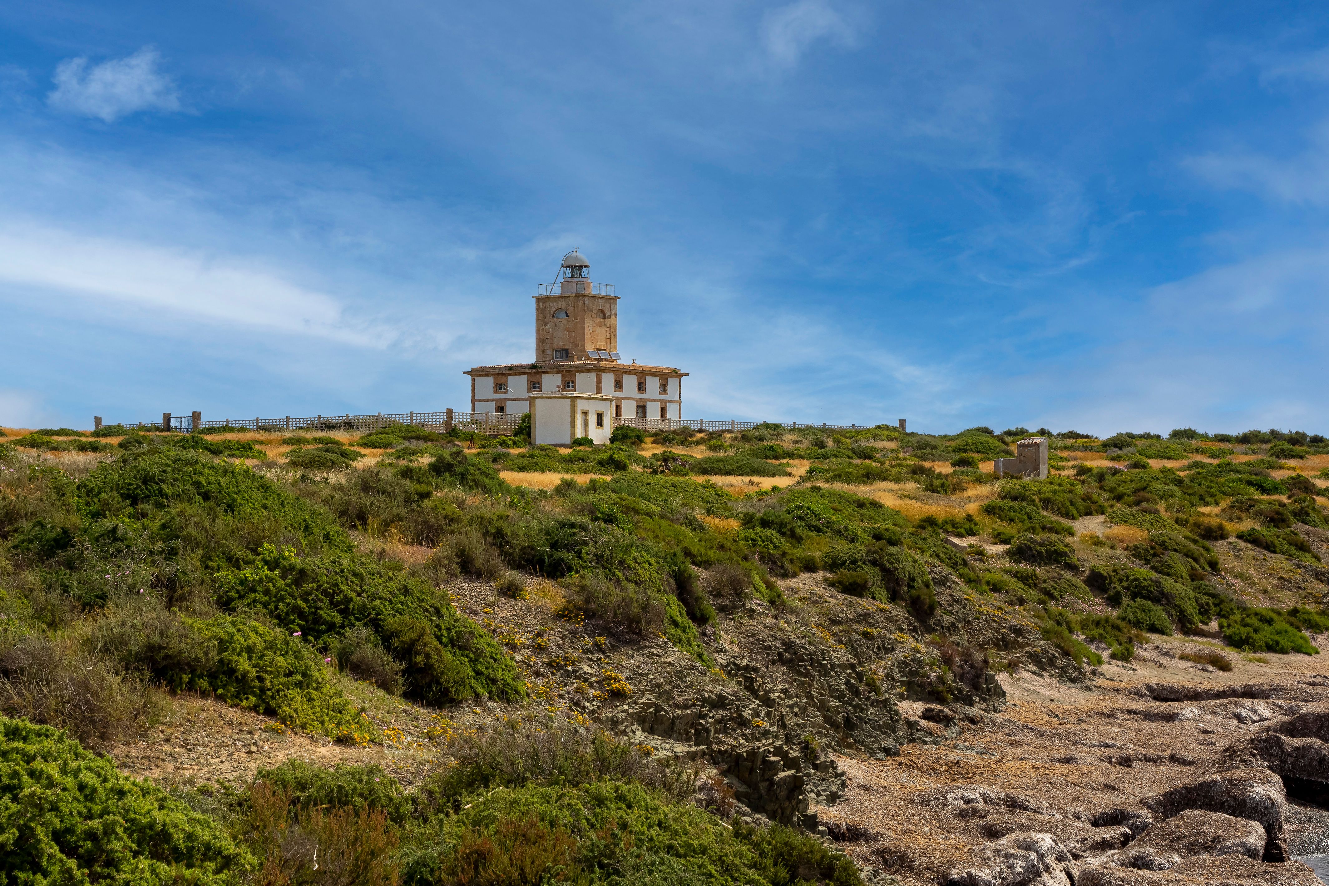 Beautiful scenic view of Tabarca Lighthouse on a clear sunny day with lush greenery in Spain.