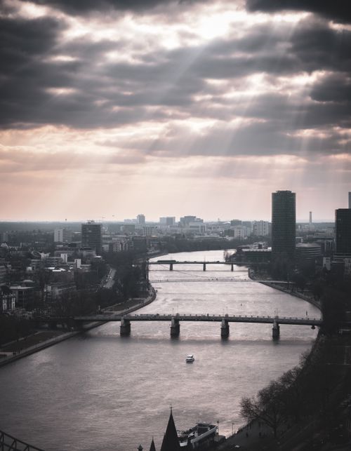 Free Aerial view of Frankfurt with urban skyline, river, and dramatic sunbeams breaking through clouds. Stock Photo