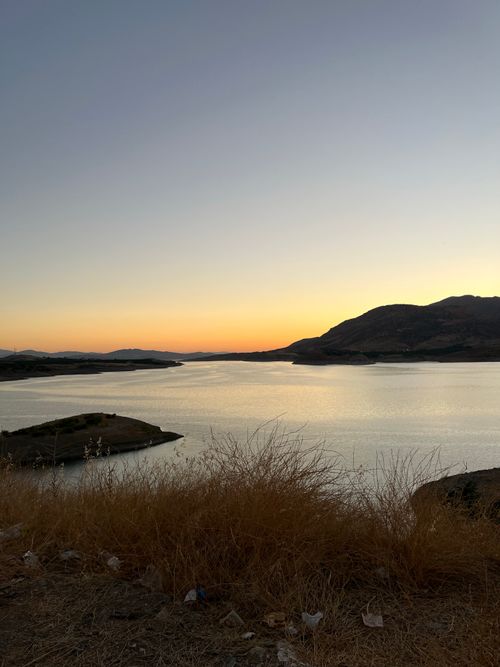 Free Peaceful view of a sunset over a calm lake surrounded by mountains. Stock Photo