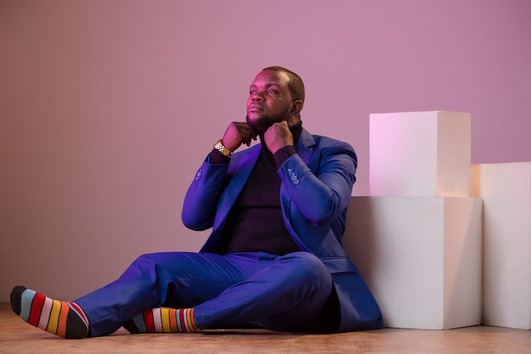 A Man In A Blue Suit Sitting On The Floor 