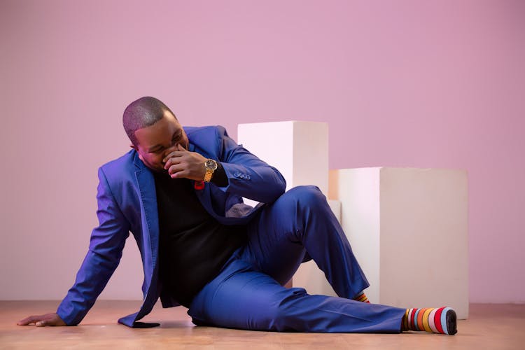 A Man In A Blue Suit Sitting On The Floor 