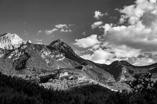 Grayscale Photo of Mountain Under the Cloudy Sky