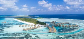 从空中俯瞰马尔代夫，热带水上别墅与海滩尽收眼底，碧绿的海水环绕着郁郁葱葱的岛屿，景色令人惊叹