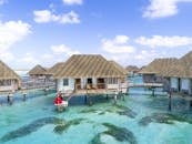 在水上别墅的热带天堂环境中，一对夫妇身着红色连衣裙