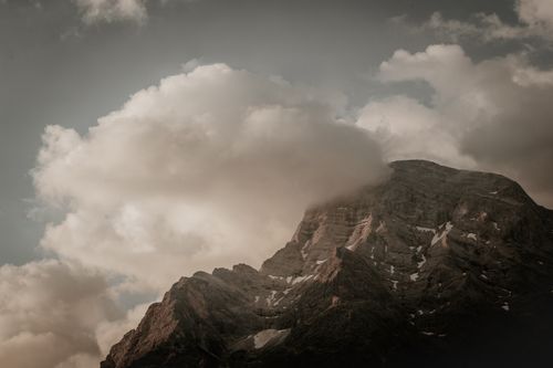 Free Majestic mountain peak shrouded in dramatic clouds under a moody sky. Stock Photo