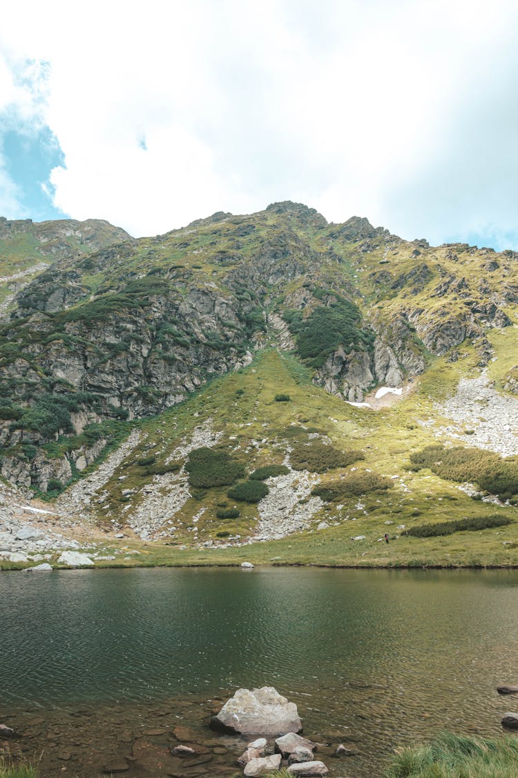 Green And Gray Mountain Beside Lake Under The Sky