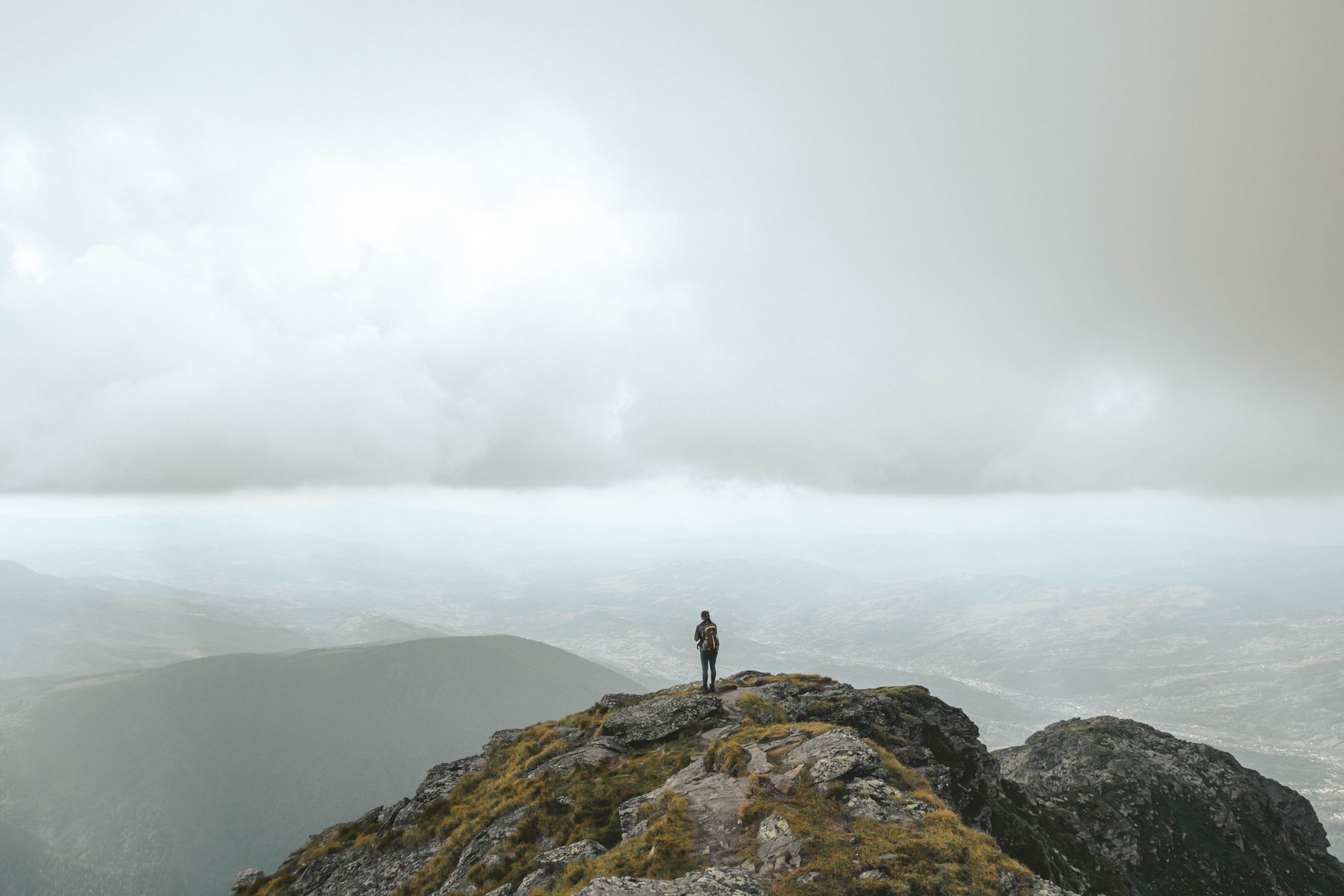A lone figure standing on a rocky headland above a sea of mist