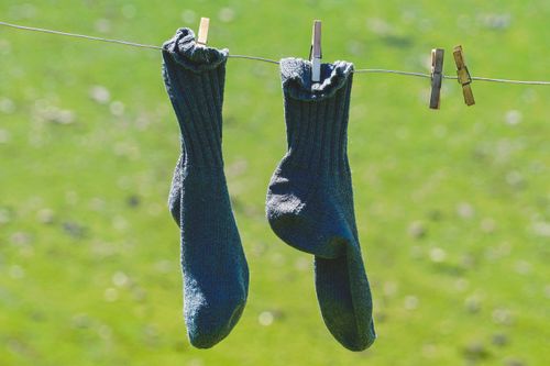 Free Woolen socks hung on a clothesline, drying in the sun with a natural green backdrop. Stock Photo