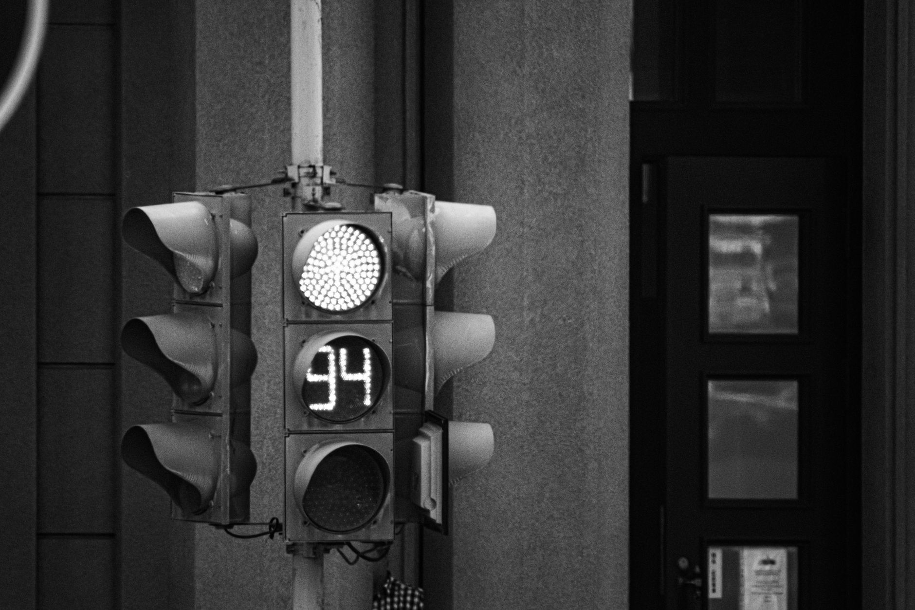 Monochrome close-up of a traffic light with a digital timer display showing 94 seconds.