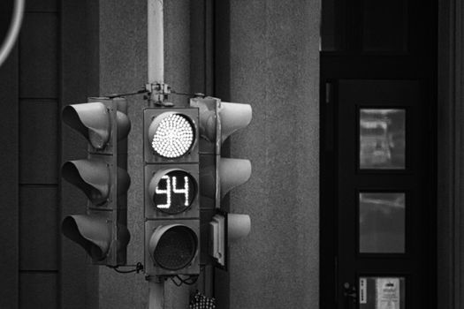Monochrome close-up of a traffic light with a digital timer display showing 94 seconds.