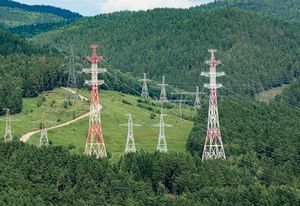 High-voltage transmission towers crossing forested hills. Photo by Radik 2707 on Pexels.