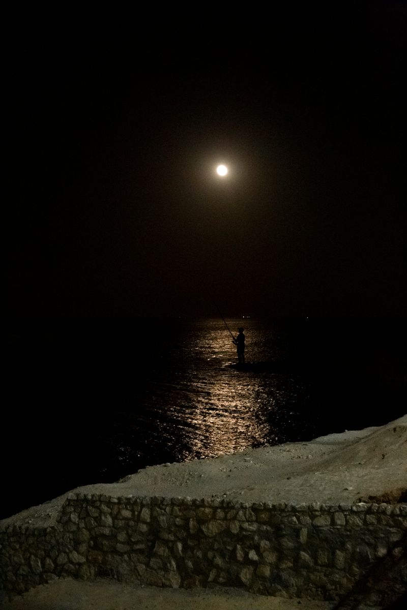 Night fishing silhouette angler with rod