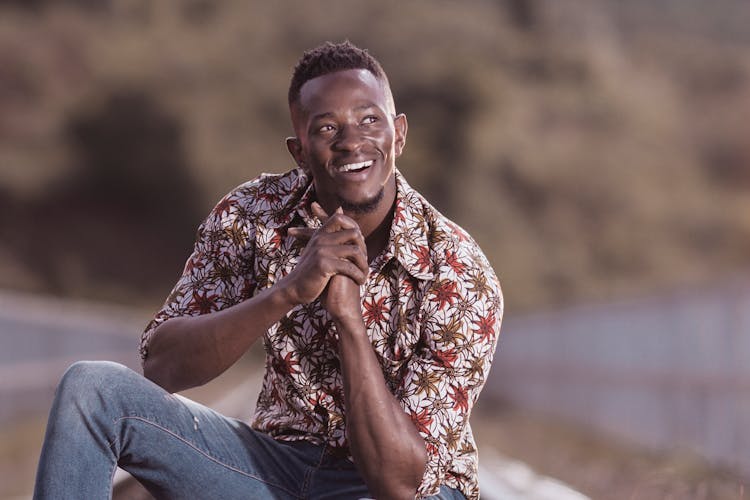 A Man In Printed Shirt Smiling With His Hands Together