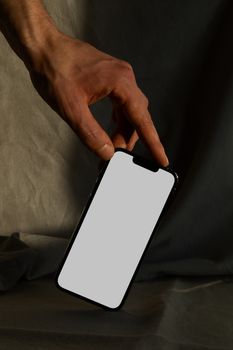 A hand holding a smartphone with a blank screen, perfect for mobile app designs and advertisements.
