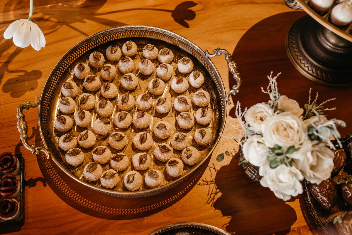 A beautifully arranged tray of sweets with decorative flowers on a wooden table.